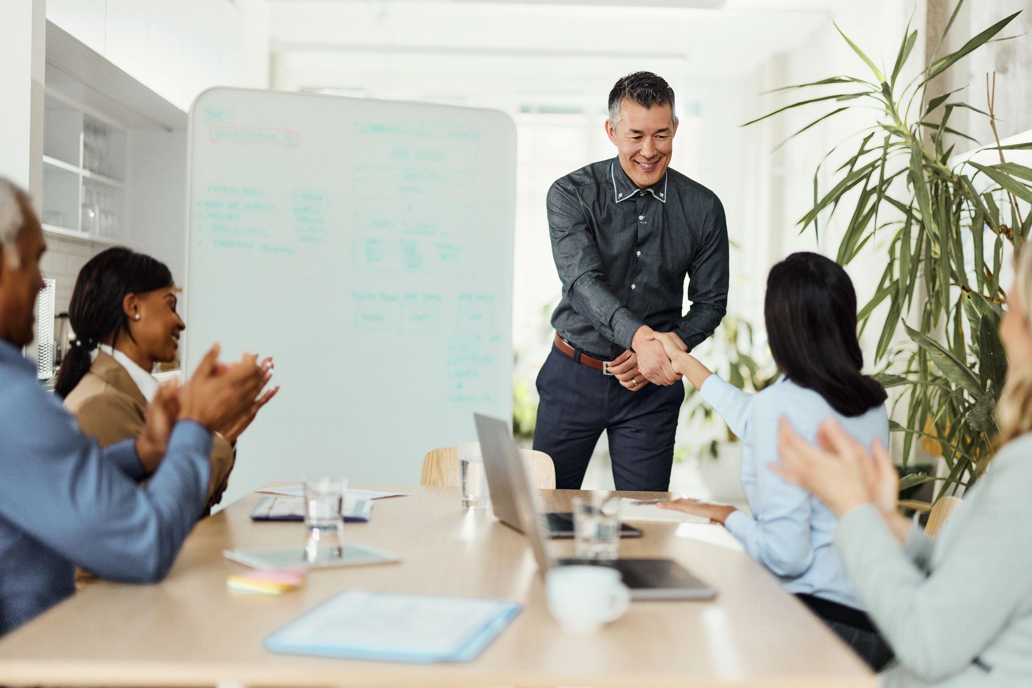 Happy Indian business professionals shaking hands during a successful client meeting in a modern office